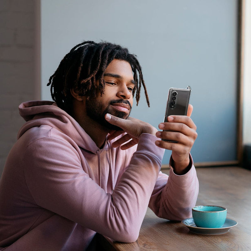 ACS02959 - Galaxy Z Fold 3 Case Ultra Hybrid in crystal clear showing a man sitting in a coffee shop staring into device in his hands