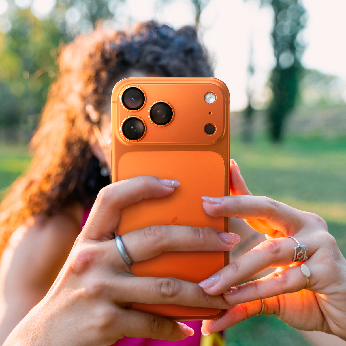 AGL10650 - iPhone 17 Pro Max Optik Pro XL EZ Fit Lens Protector in orange showing a person holding the case with both hands